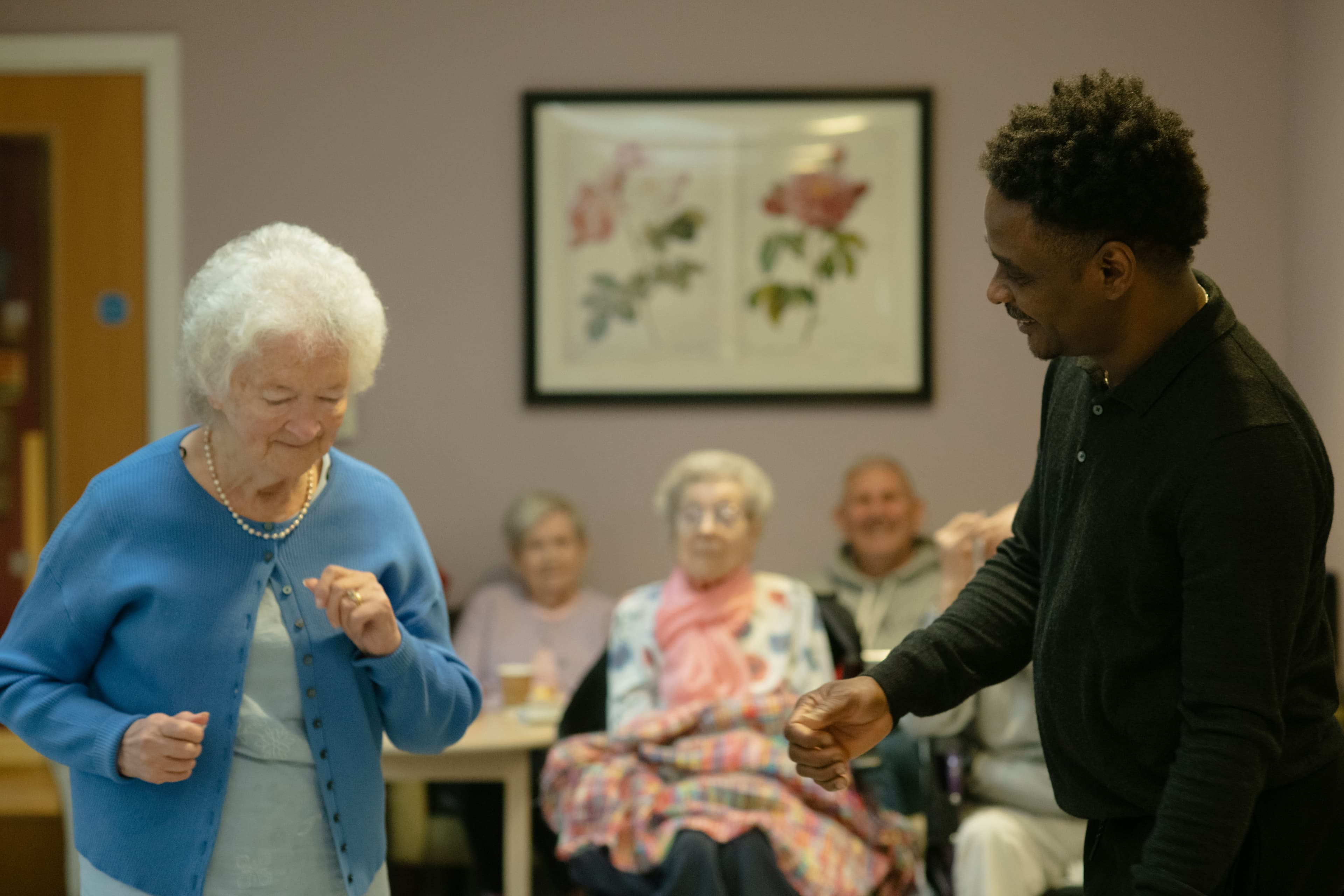 A caregiver dancing joyfully with an elderly resident at a care home
